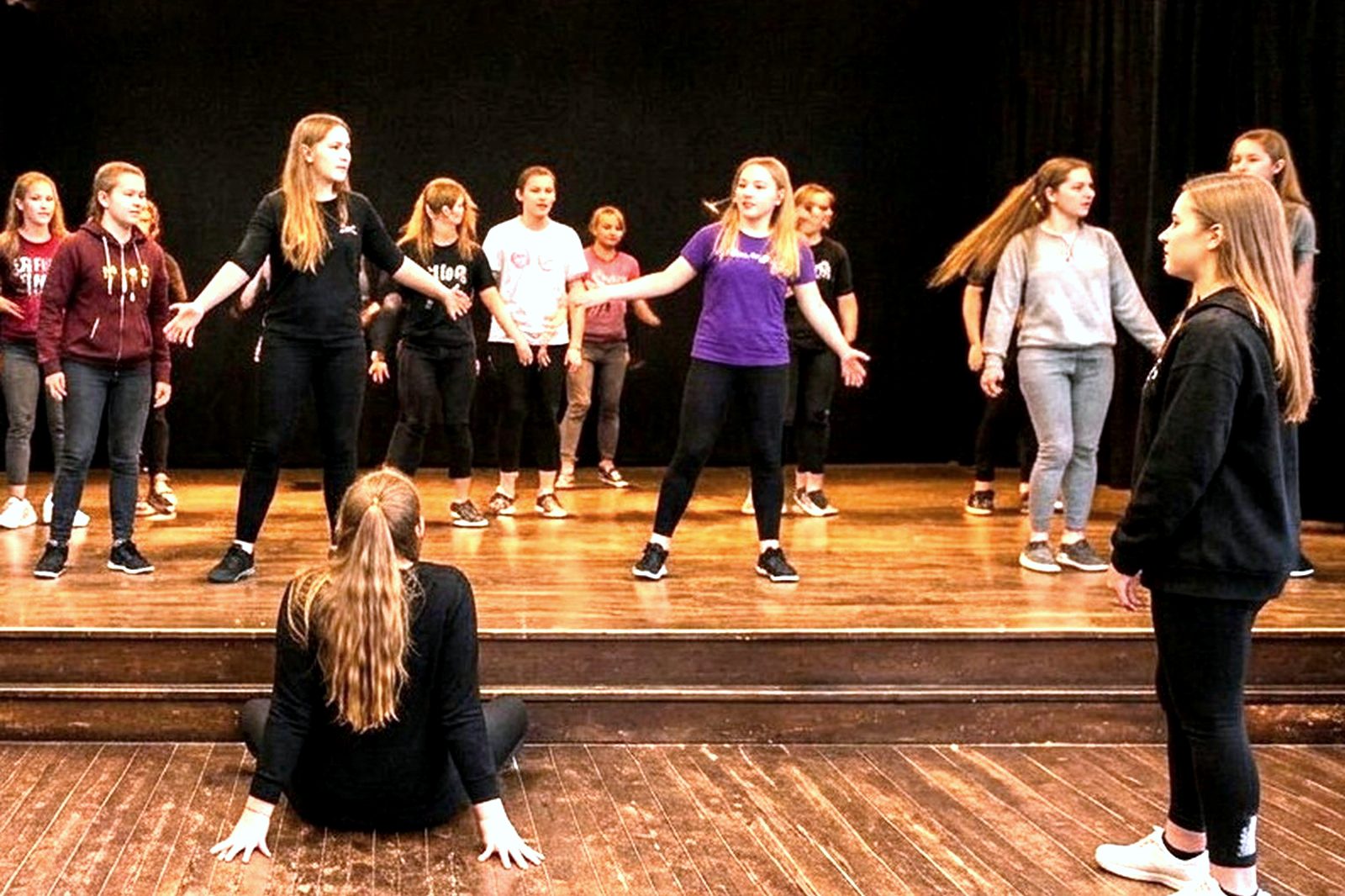 Students rehearsing a routine on stage under theatre lighting